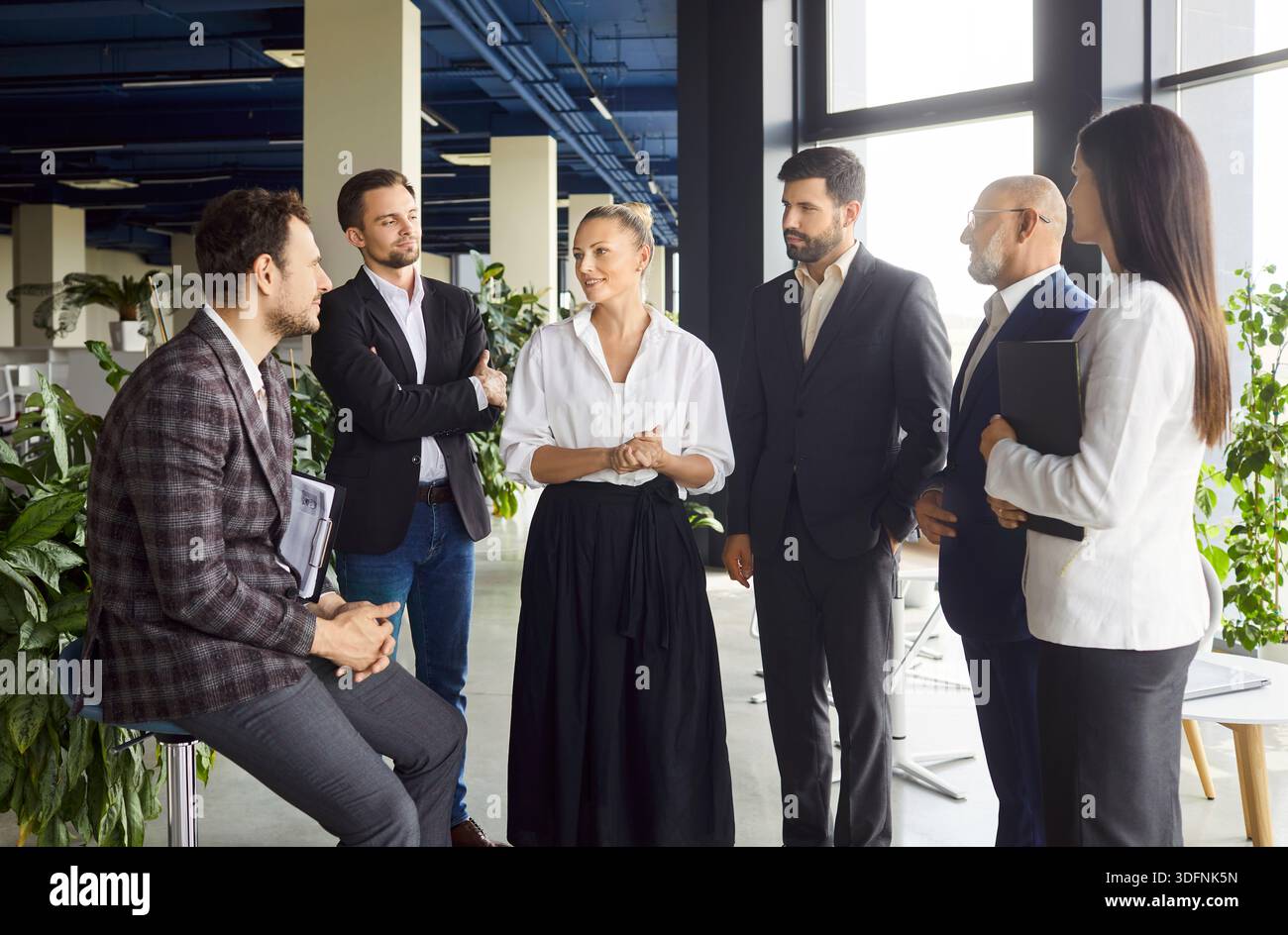 Team of successful business people standing in office room, discussing something, enjoying team work Stock Photo