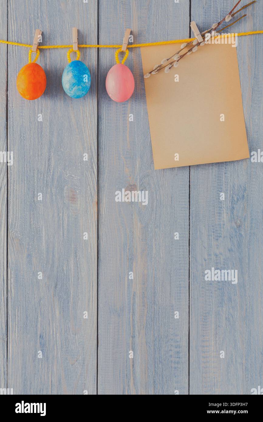 Colorful Easter Eggs Hanging on a String With an Empty Note on a Wooden Background Stock Photo