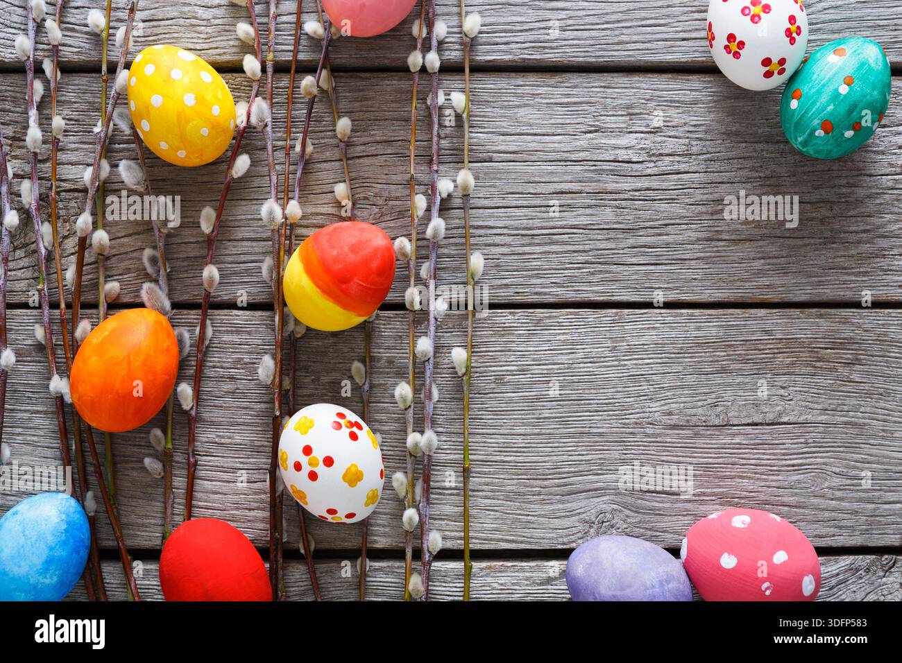 Colorful Easter Eggs Arranged With Willow Branches on Rustic Wooden Background Stock Photo