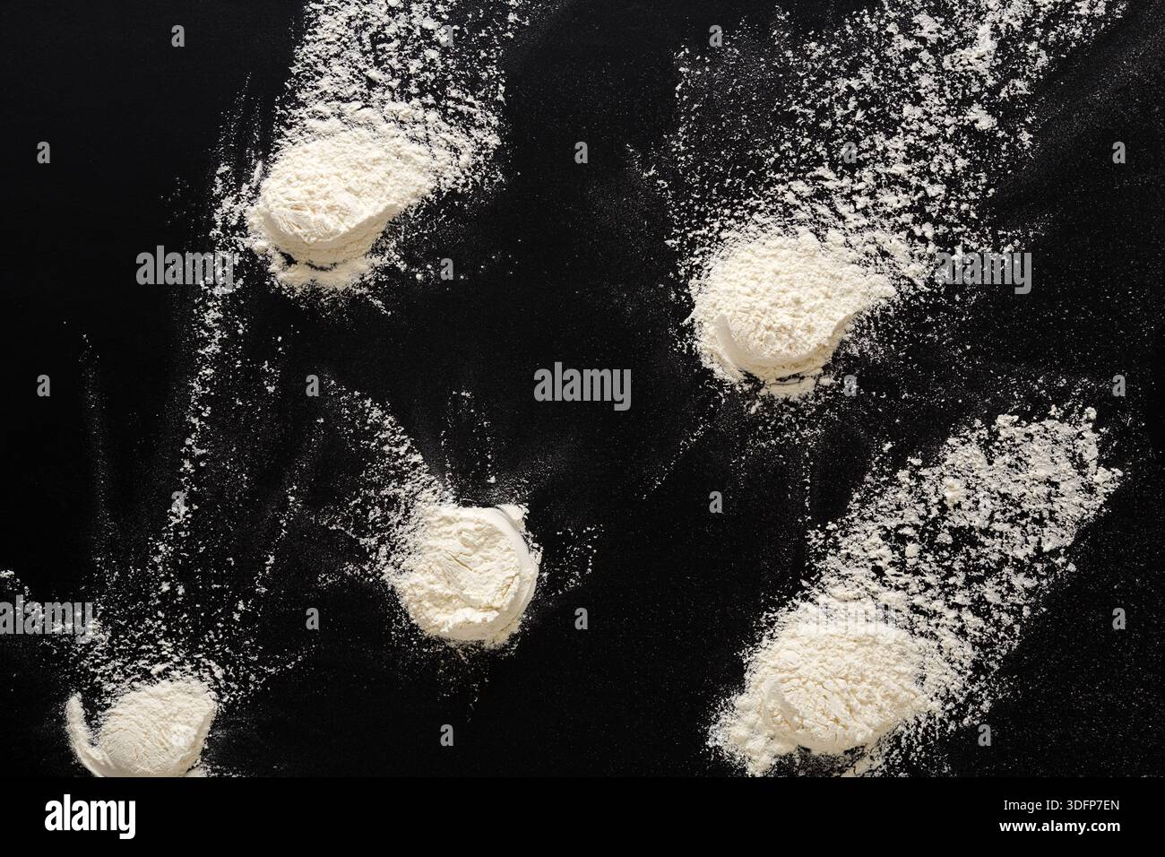 Sprinkled wheat flour splash spots on black background Stock Photo