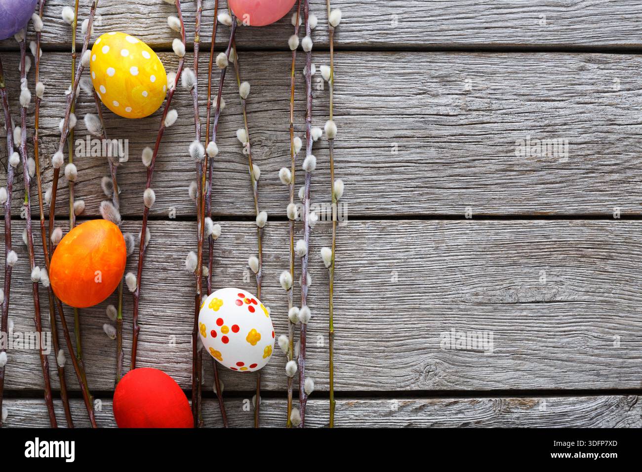 Colorful Easter Eggs Arranged With Willow Branches on Rustic Wooden Surface Stock Photo
