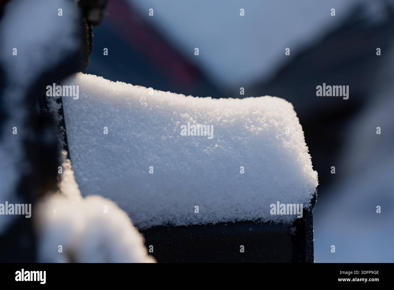 Snow covered metal object in close view, clean white snow cap with glittering crystals and soft bokeh background, minimalist cold season texture scene Stock Photo