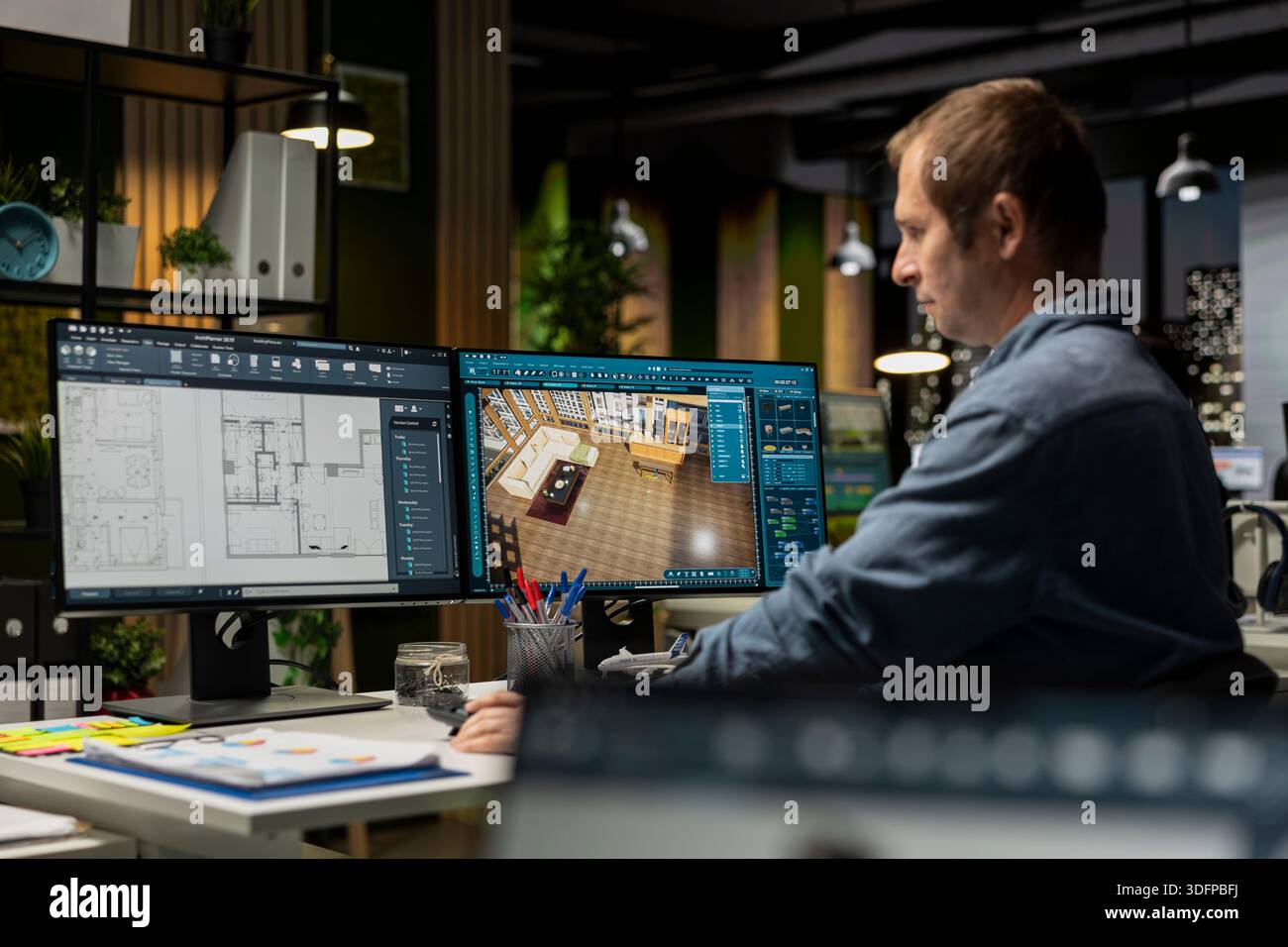 Expert designer decorating apartment floor plan using blueprints on pc, using architectural software to configure elements. Focused man uses interface to enable rendering and 3D modeling. Stock Photo