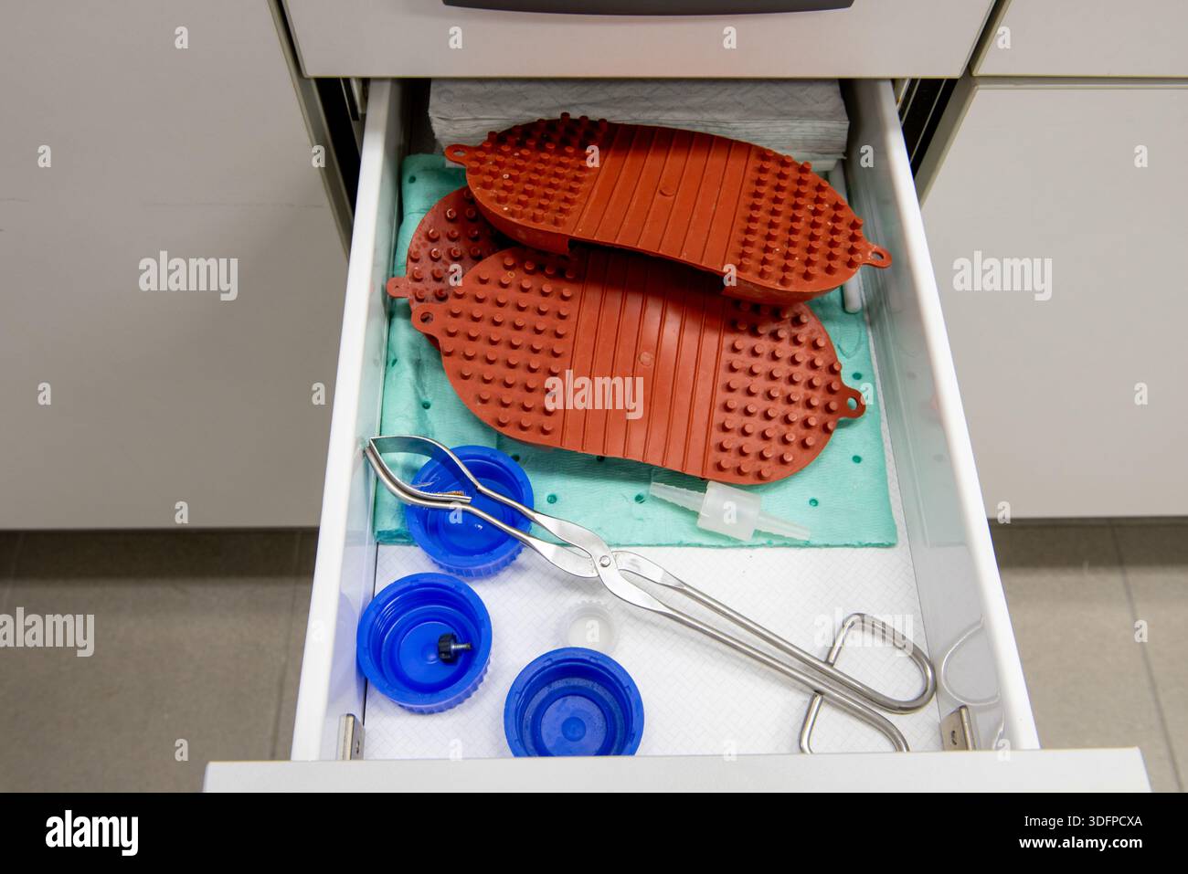 Laboratory equipment in the drawer in the laboratory. Silicone hot pads and forceps in the drawer. Stock Photo