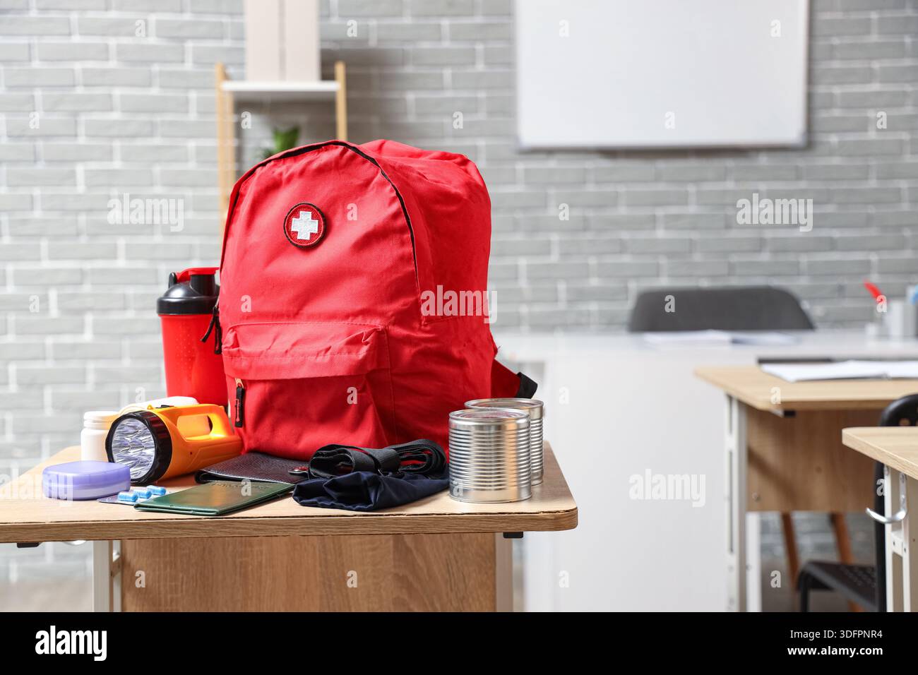 Emergency backpack with necessities on desk in classroom Stock Photo