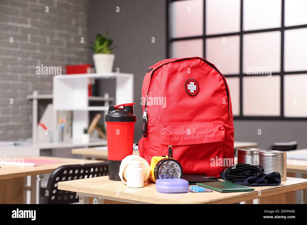 Emergency backpack with necessities on desk in classroom Stock Photo