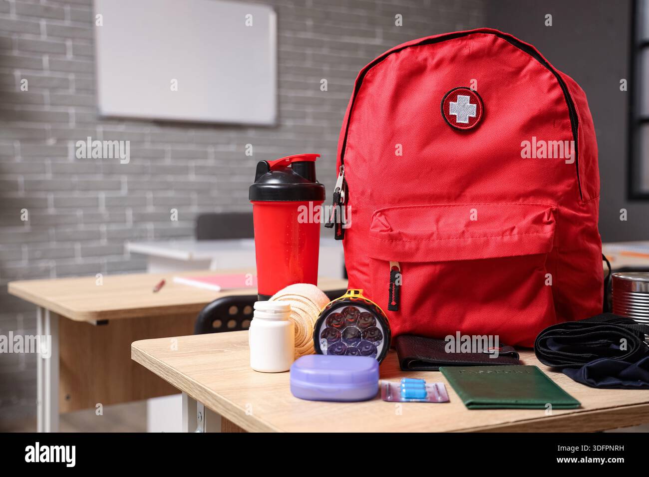 Emergency backpack with necessities on desk in classroom Stock Photo