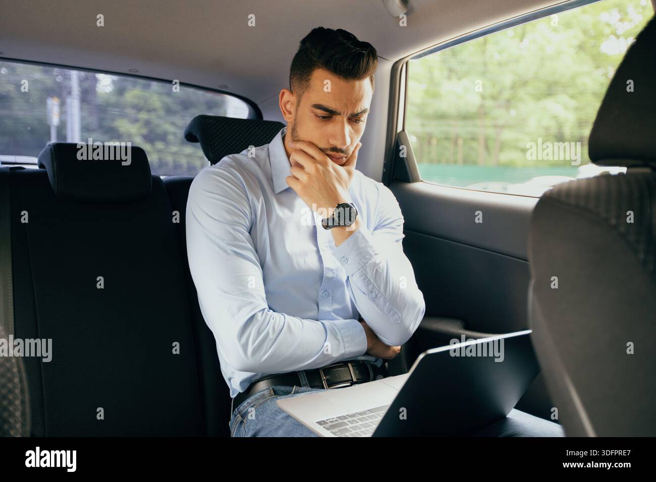 Pensive middle-eastern businessman working at car, using laptop Stock Photo