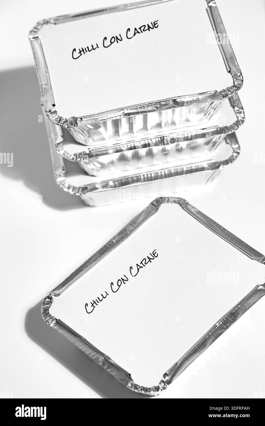 Individual foil tray containers filled with homemade chilli con carne ready for freezing. Ideas for cutting the cost of food. Stock Photo