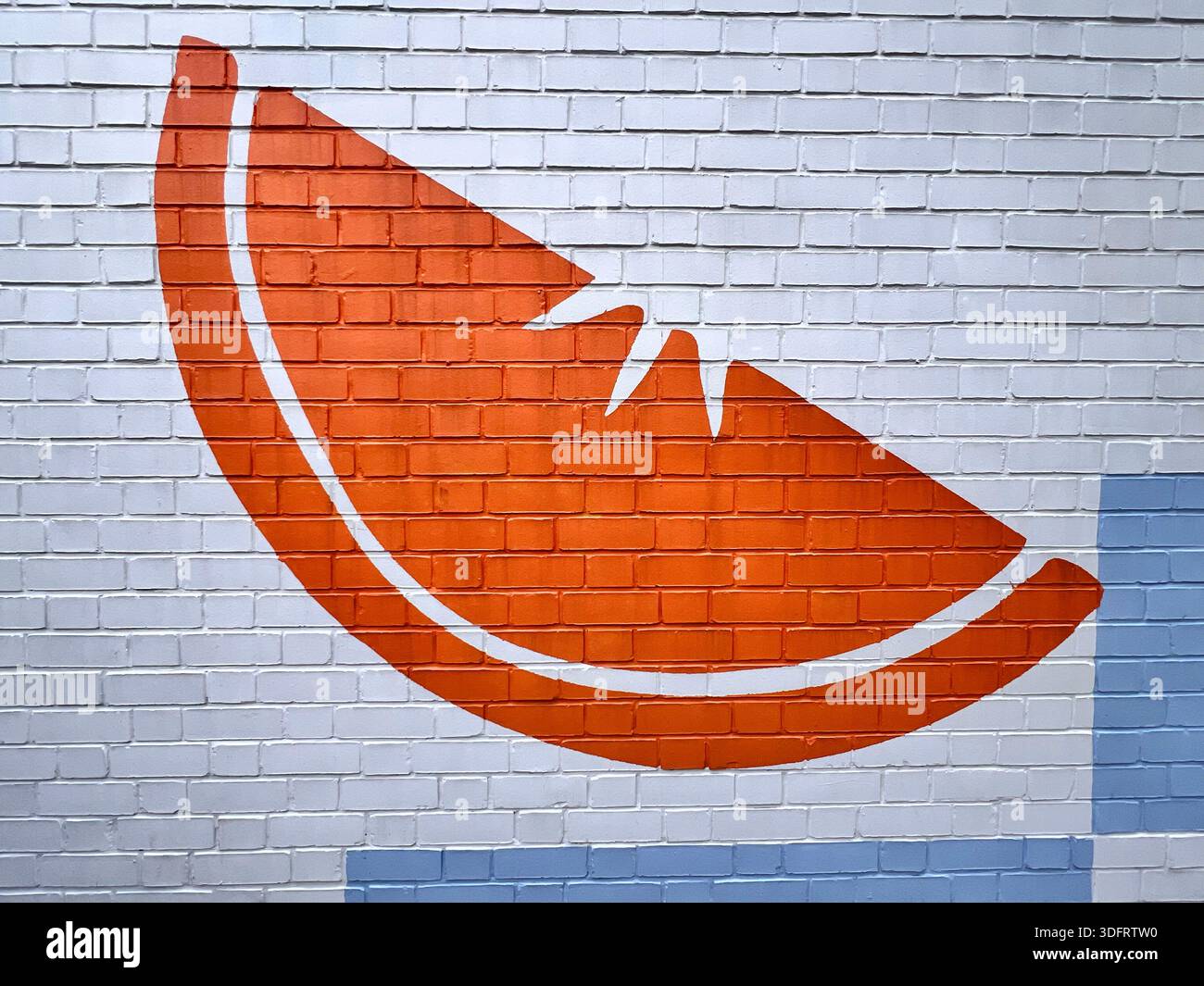Orange slice of orange painted on the wall bricks, or is it watermelon? You decide. Wall mural iconography. - Smartphone Captured Stock Image