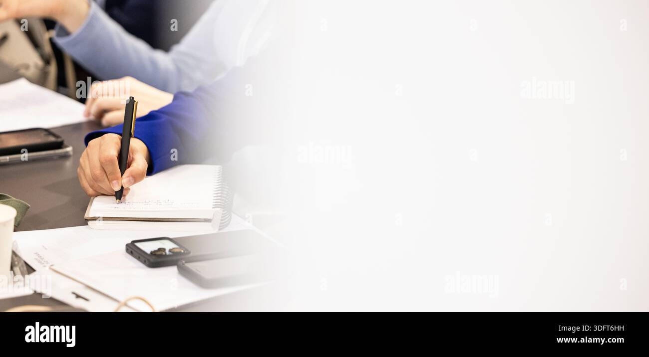 Person's hand writing in a spiral notebook, capturing information during a professional meeting Stock Photo