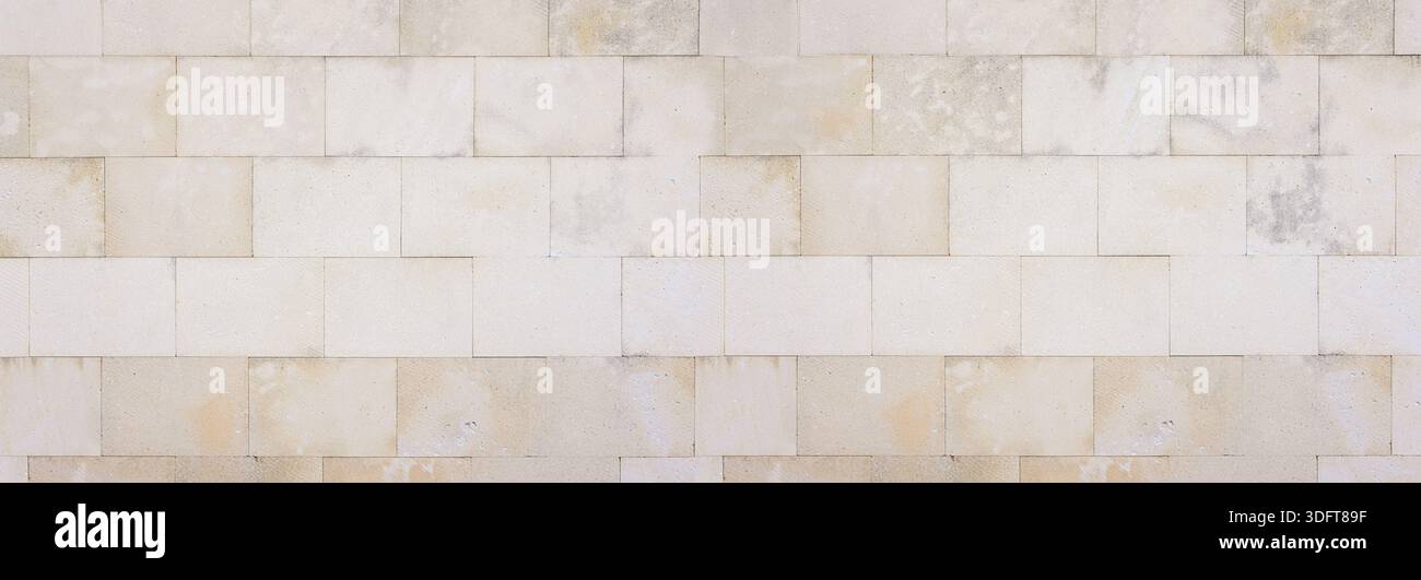Pale beige rectangular stone blocks forming a textured architectural wall Stock Photo