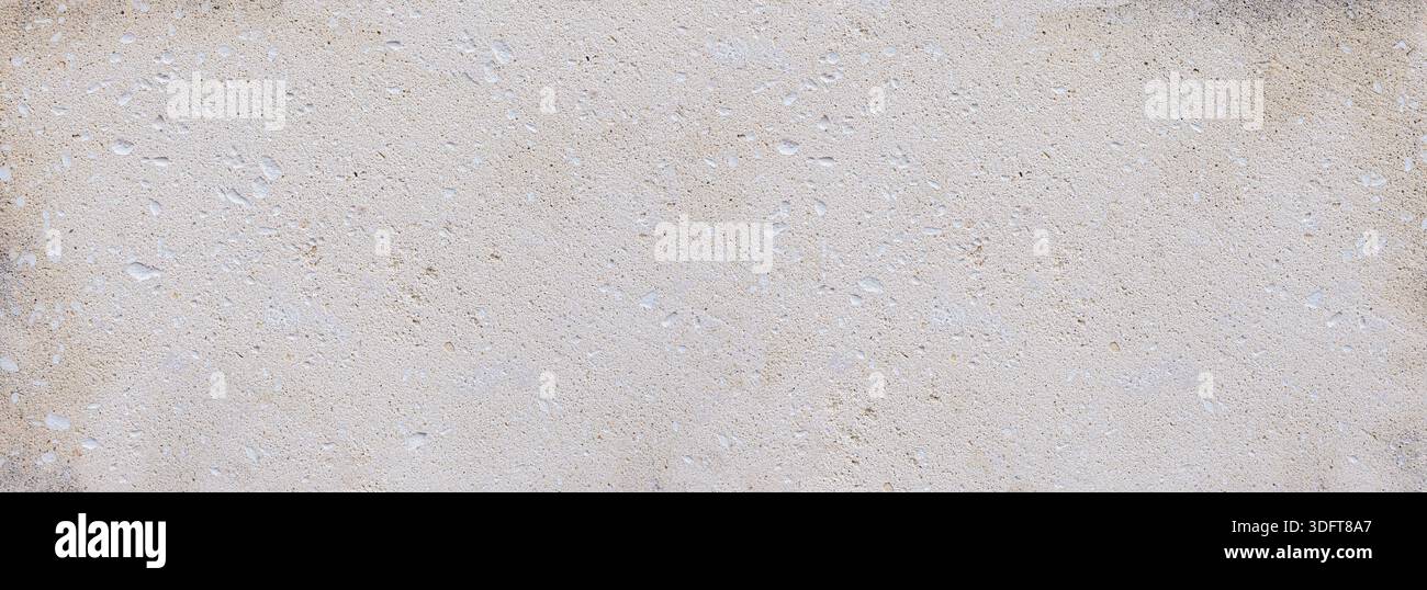 Rough limestone texture covering a weathered cement wall surface, creating a subtle background Stock Photo