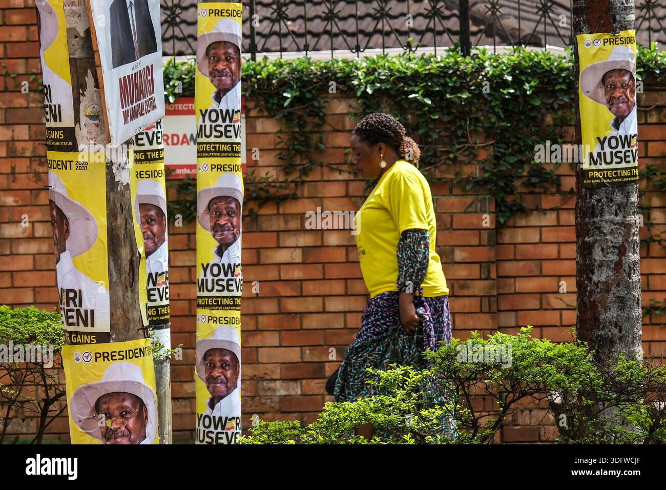Nrm Rally A supporter passes utility poles plastered with posters of Uganda's ...
