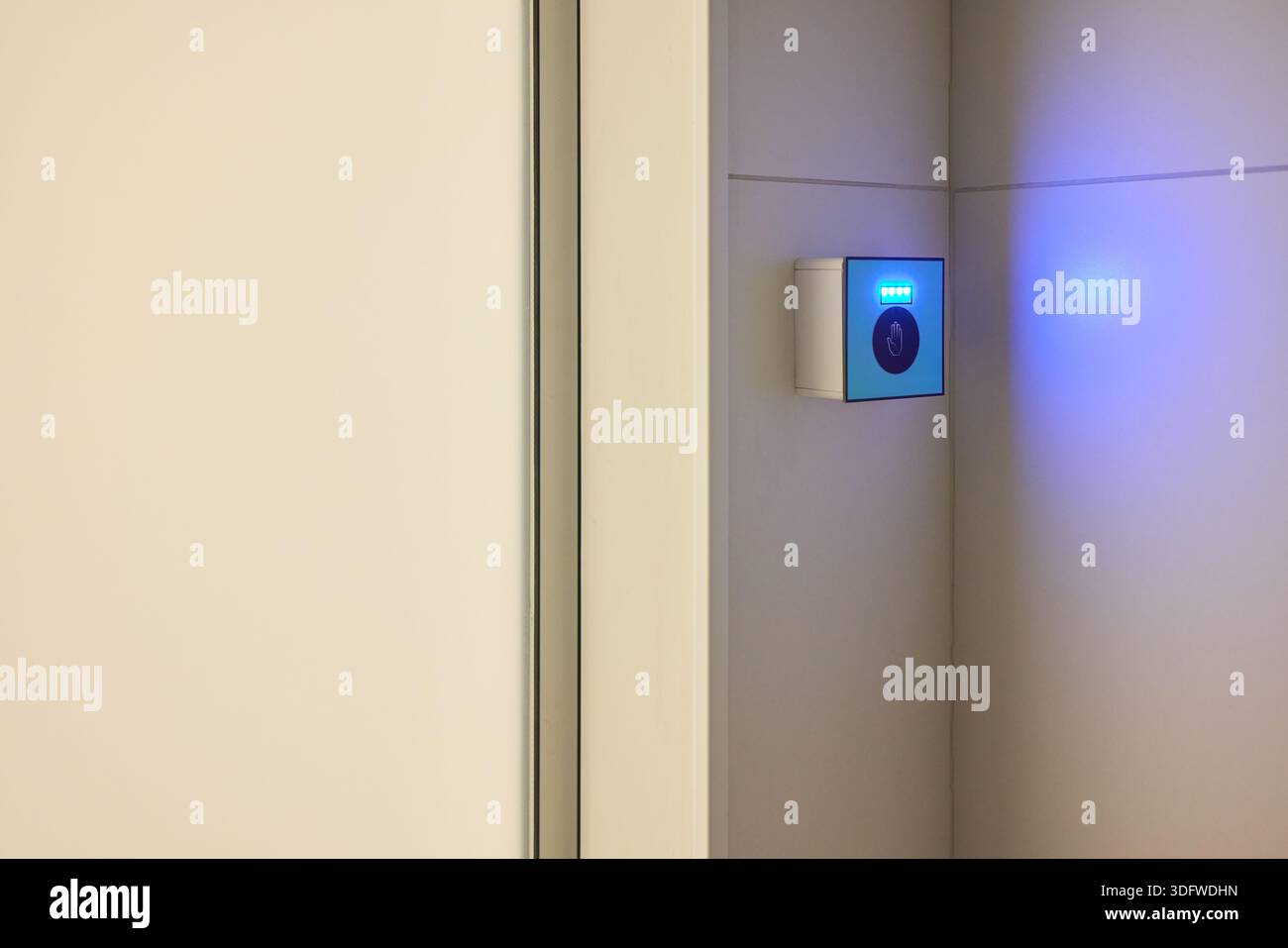This is a modern smart touch sensor device installed on a wall, featuring a blue LED indicator Stock Photo