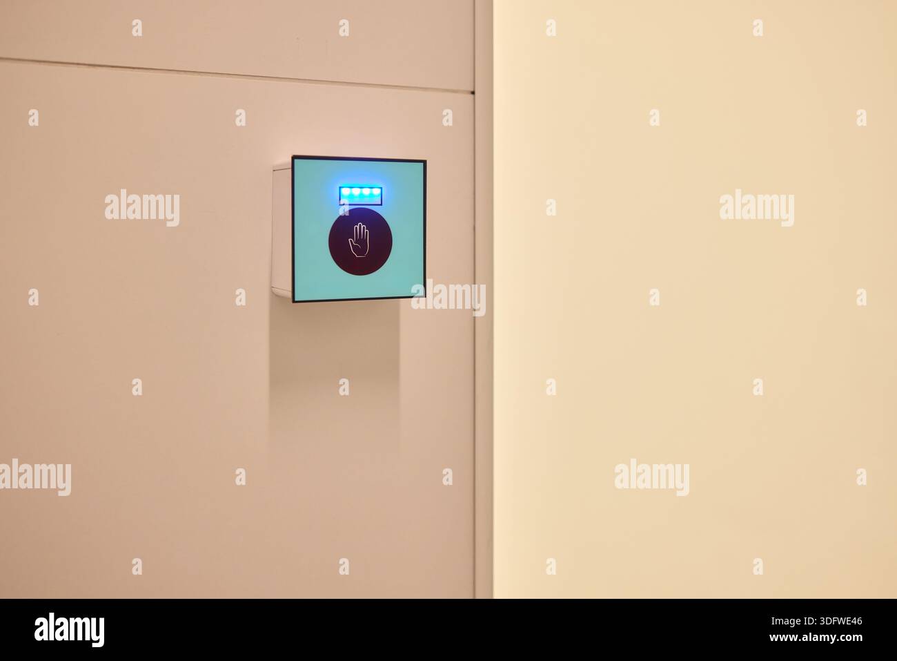 This is a modern smart touch sensor device installed on a wall, featuring a blue LED indicator Stock Photo