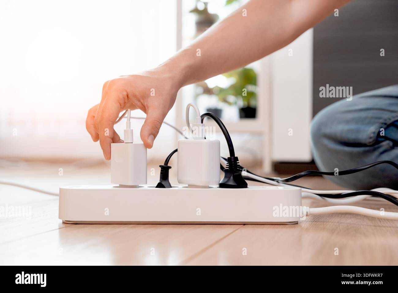 Plugging electrical plug on floor, socket at home. Energy efficiency concept Stock Photo