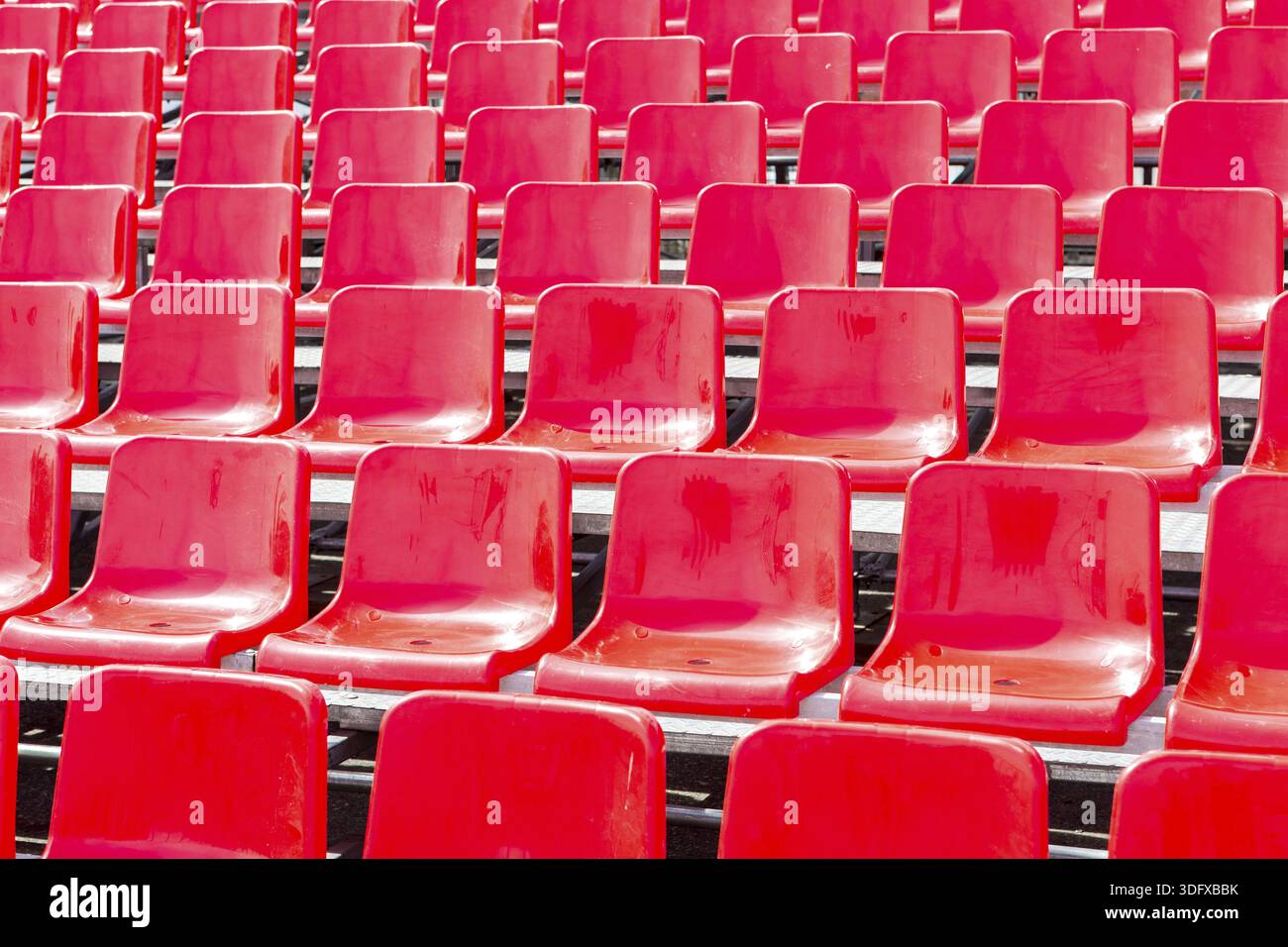 Rows empty bright red plastic seats in a stadium Stock Photo