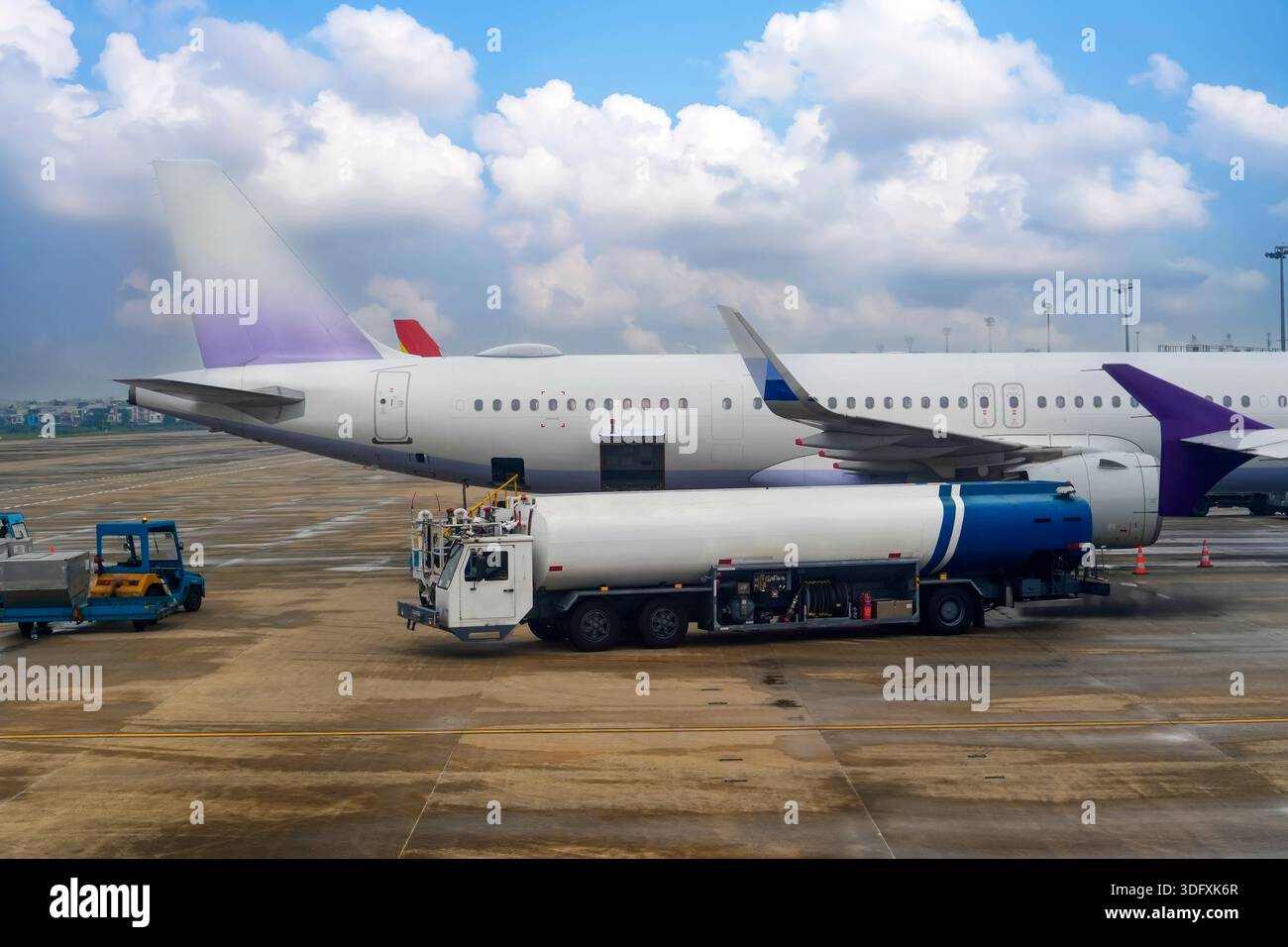 Refueling tanker truck next to passenger plane at airport pumping fuel ...