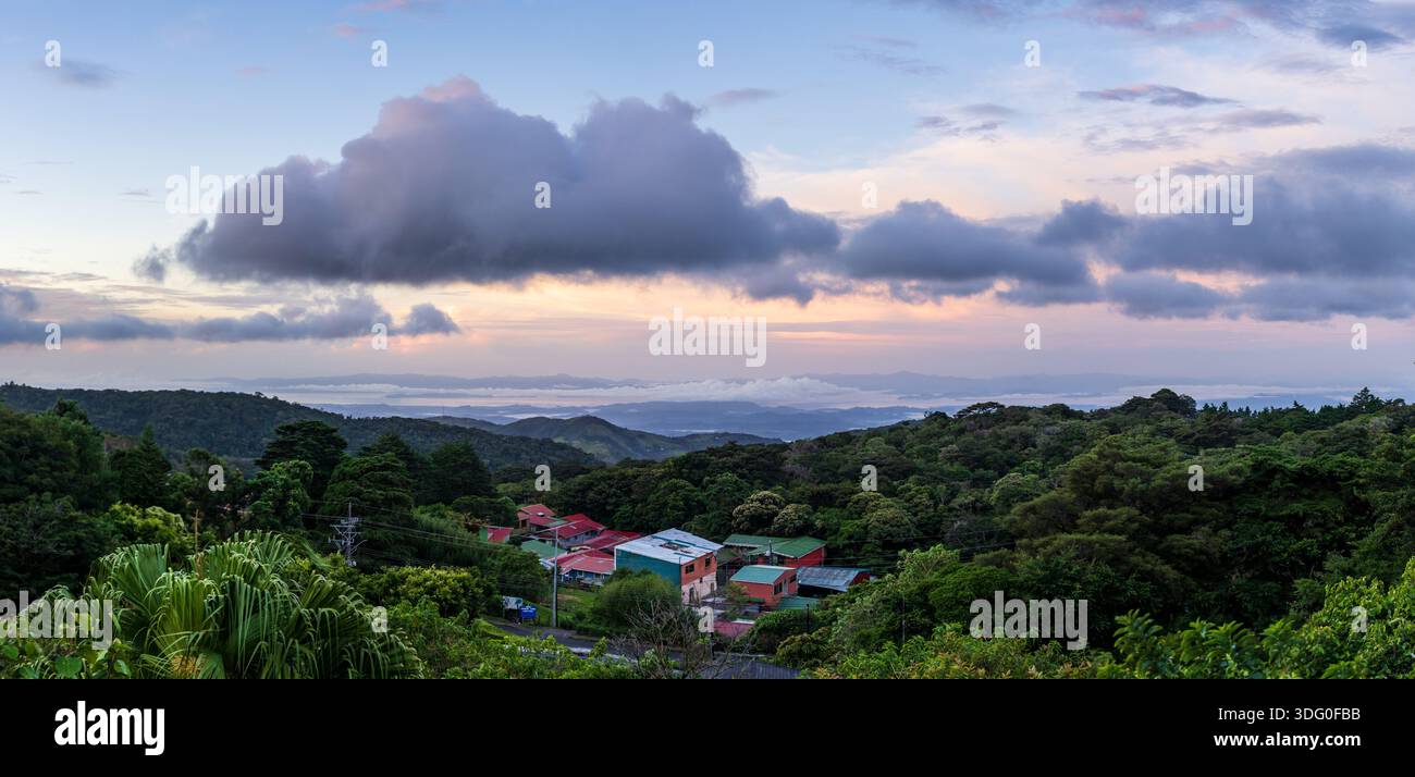 View west from Monteverde resort at sunrise over the hills towards Pacific ocean in broad panoramic format Stock Photo