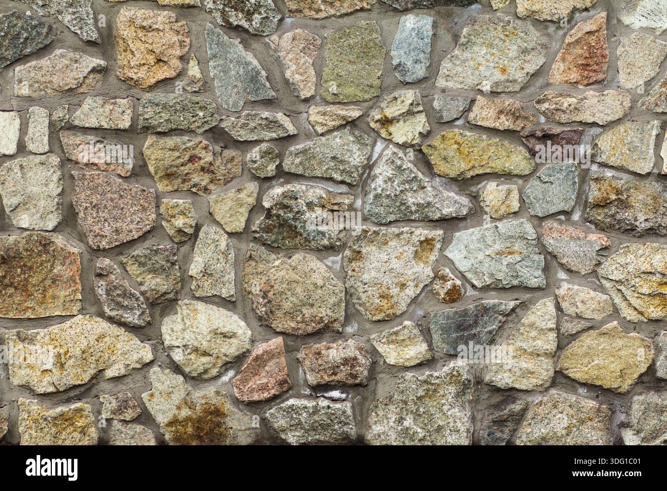Front view of gray stone wall with cement solution. Natural stone texture Stock Photo
