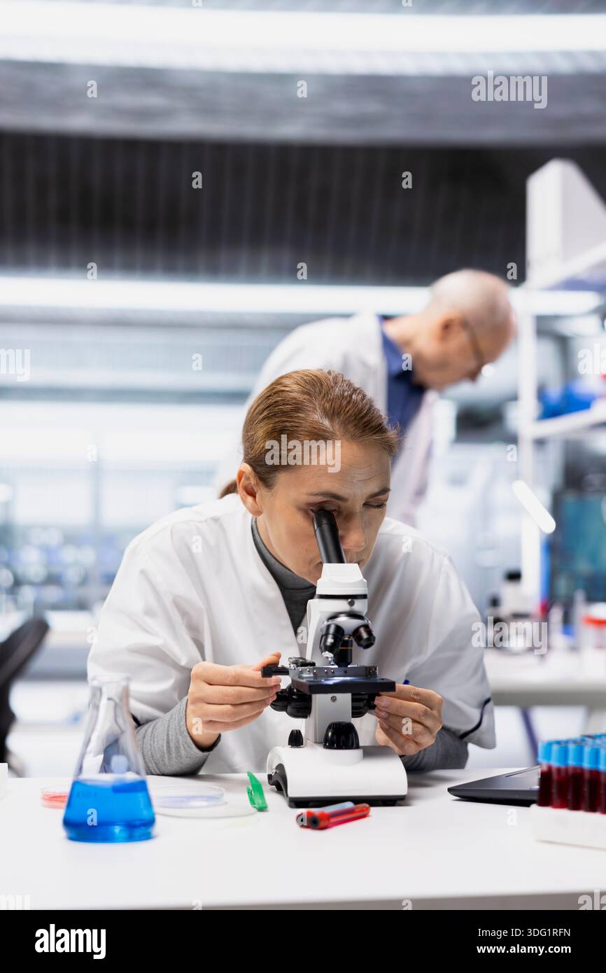 Tissue Tech Histology technician examining stained tissue sections on glass slide ...