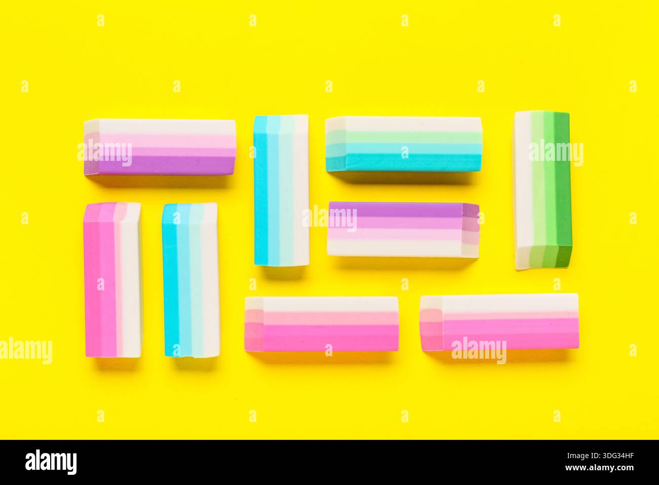 Many colorful rubber erasers on yellow background Stock Photo