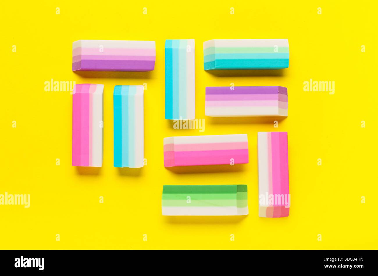 Many colorful rubber erasers on yellow background Stock Photo