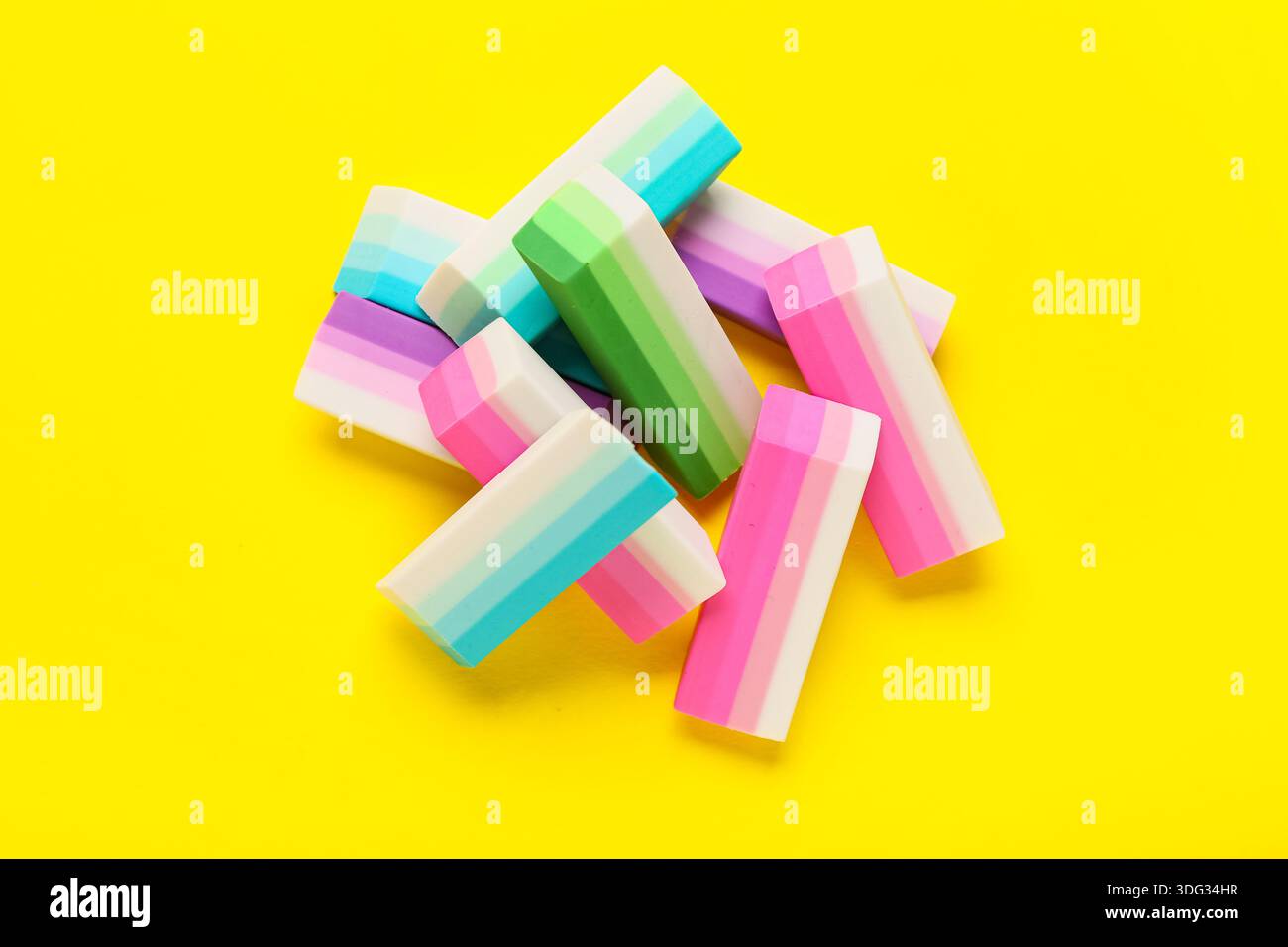 Many colorful rubber erasers on yellow background Stock Photo