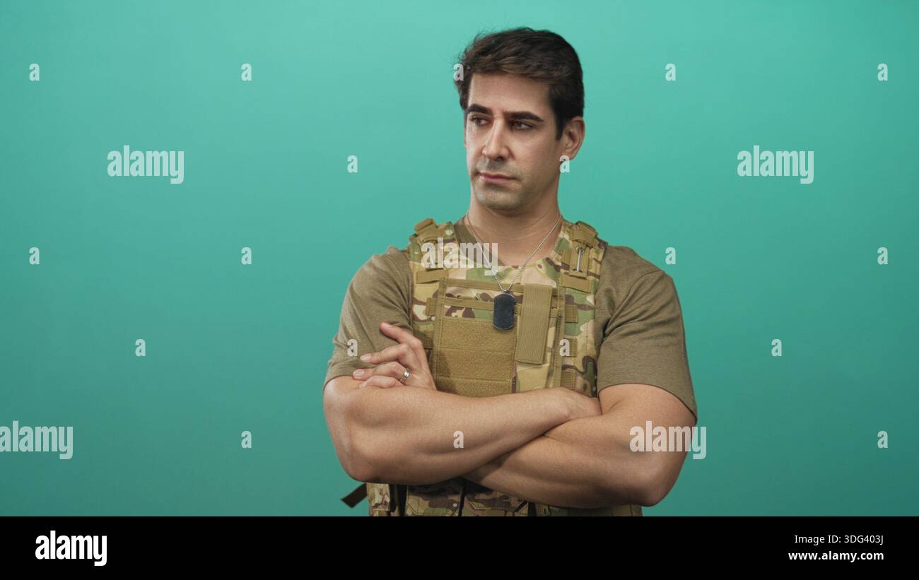 Man standing with crossed arms and visible dog tags, wearing camouflage ...