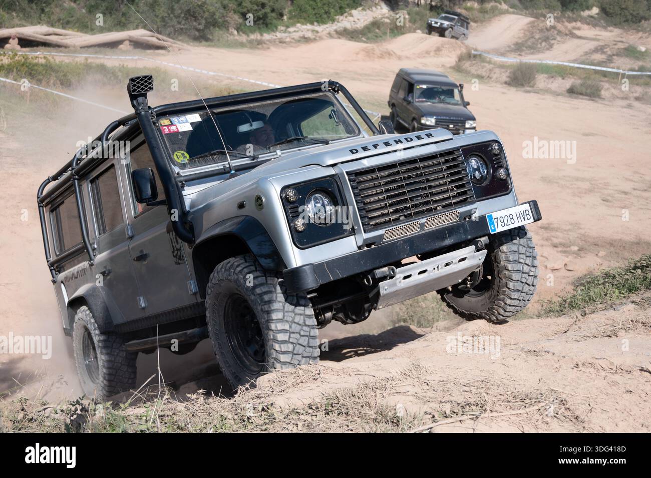 Modified silver Land Rover Defender 110 LWB climbing a steep dirt hill ...