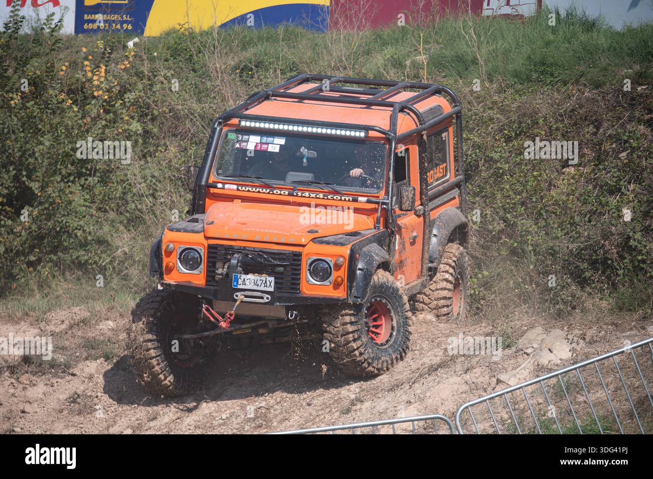 Front view of a modified orange Land Rover Defender performing extreme ...