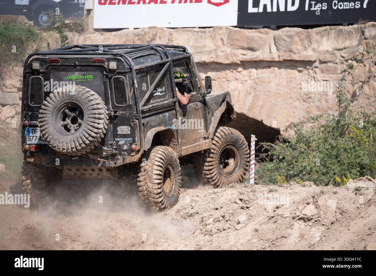 Rear side view of a black modified Land Rover Defender 90 climbing a ...