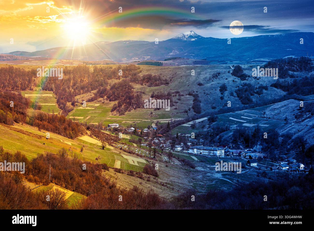 rural landscape with village in valley. day and night time change concept. outdoor adventure in countryside with rolling hill, snowy mountain under su Stock Photo