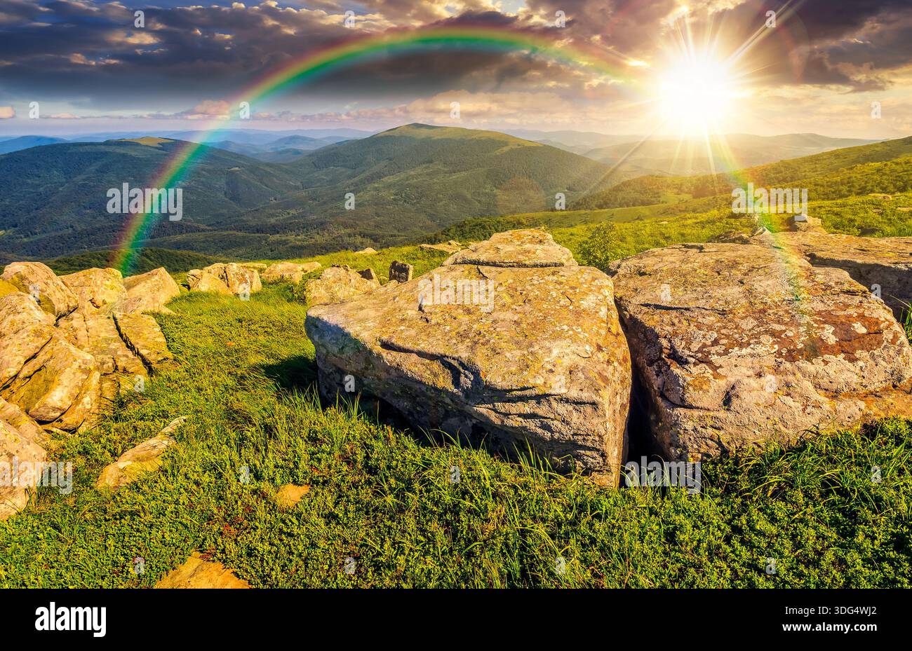 huge stones among green grass on top of the hillside meadow near the peak of mountain ridge at sunset. beautiful summer landscape in evening light. st Stock Photo