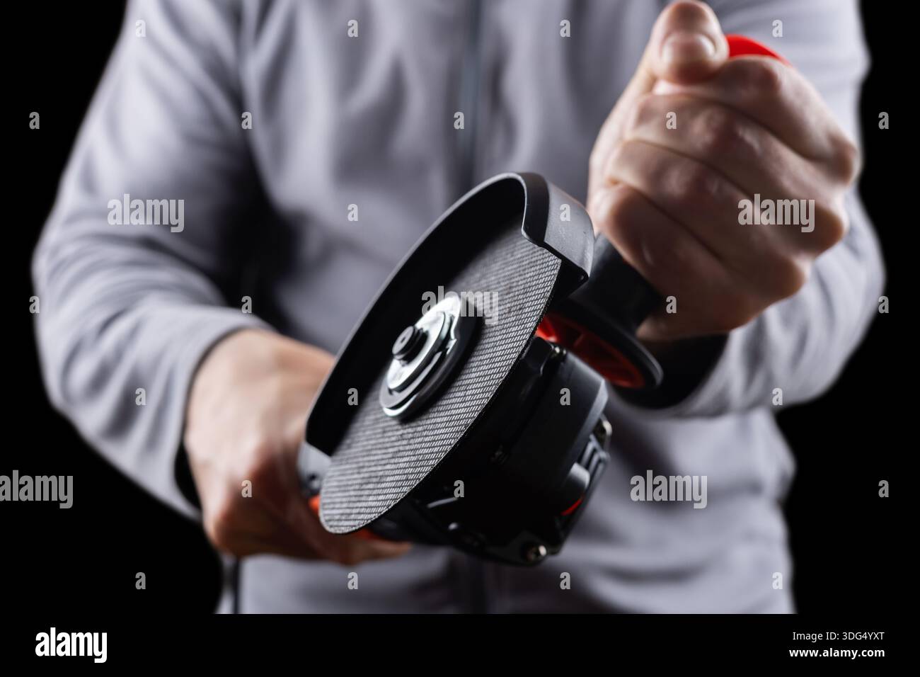 worker hold grinder tool on dark background. Stock Photo
