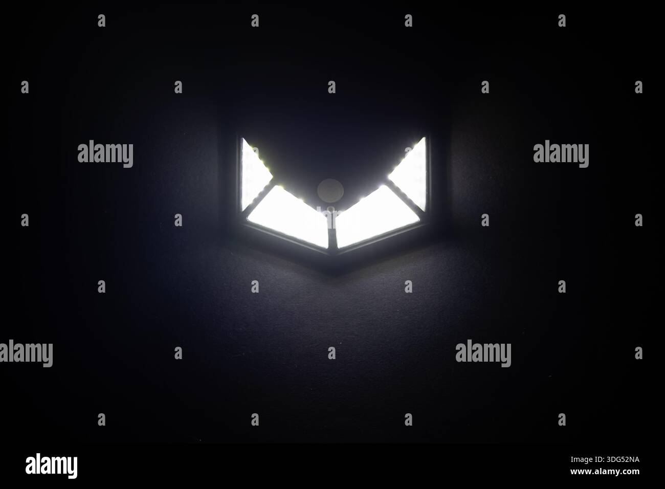 Small solar powered led light with motion sensor on dark background. Stock Photo