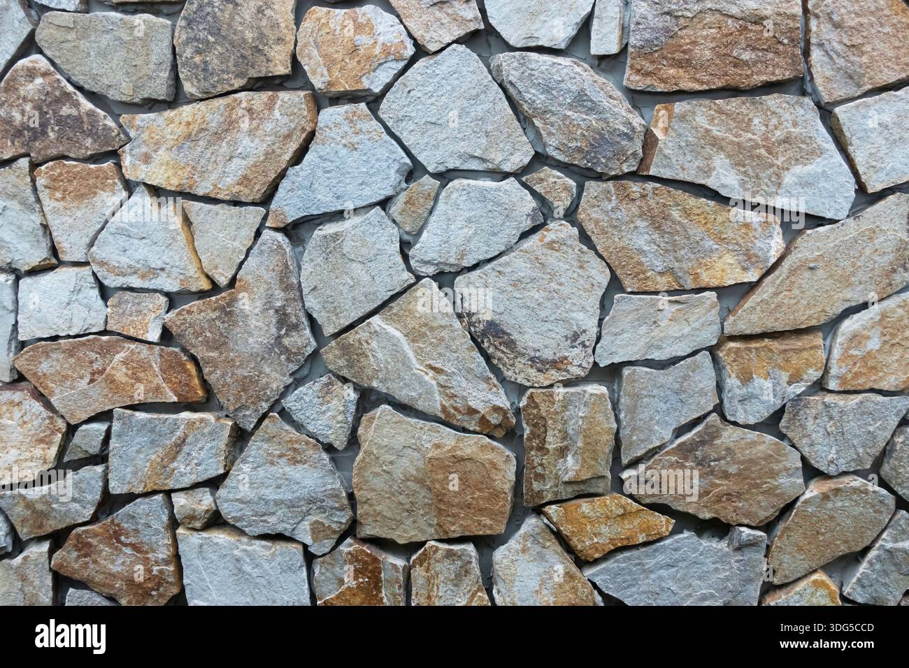 Natural stone wall with irregular rock pattern, ideal as an architectural or rustic background Stock Photo