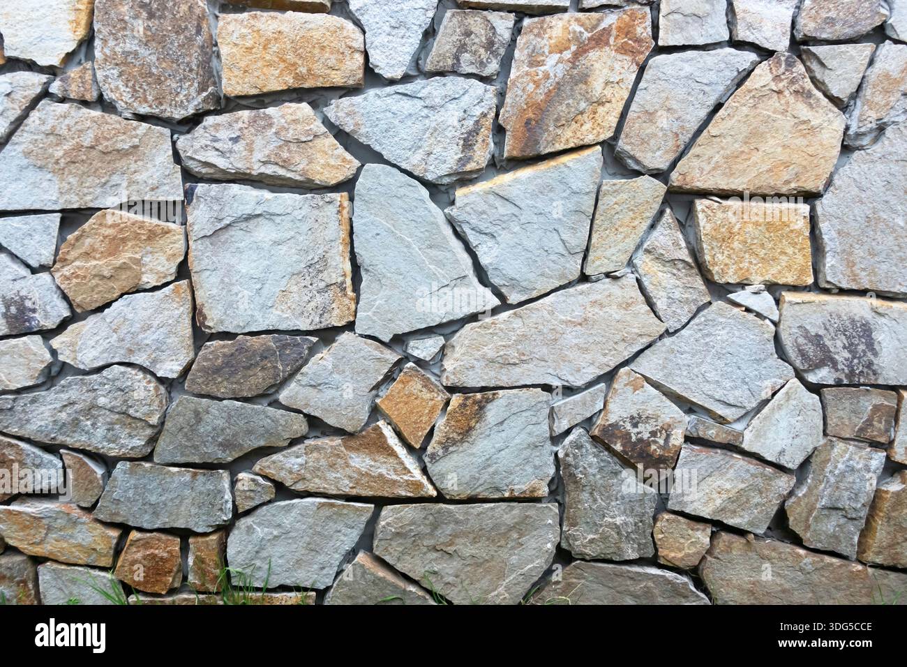 Natural stone wall with irregular rock pattern, ideal as an architectural or rustic background Stock Photo