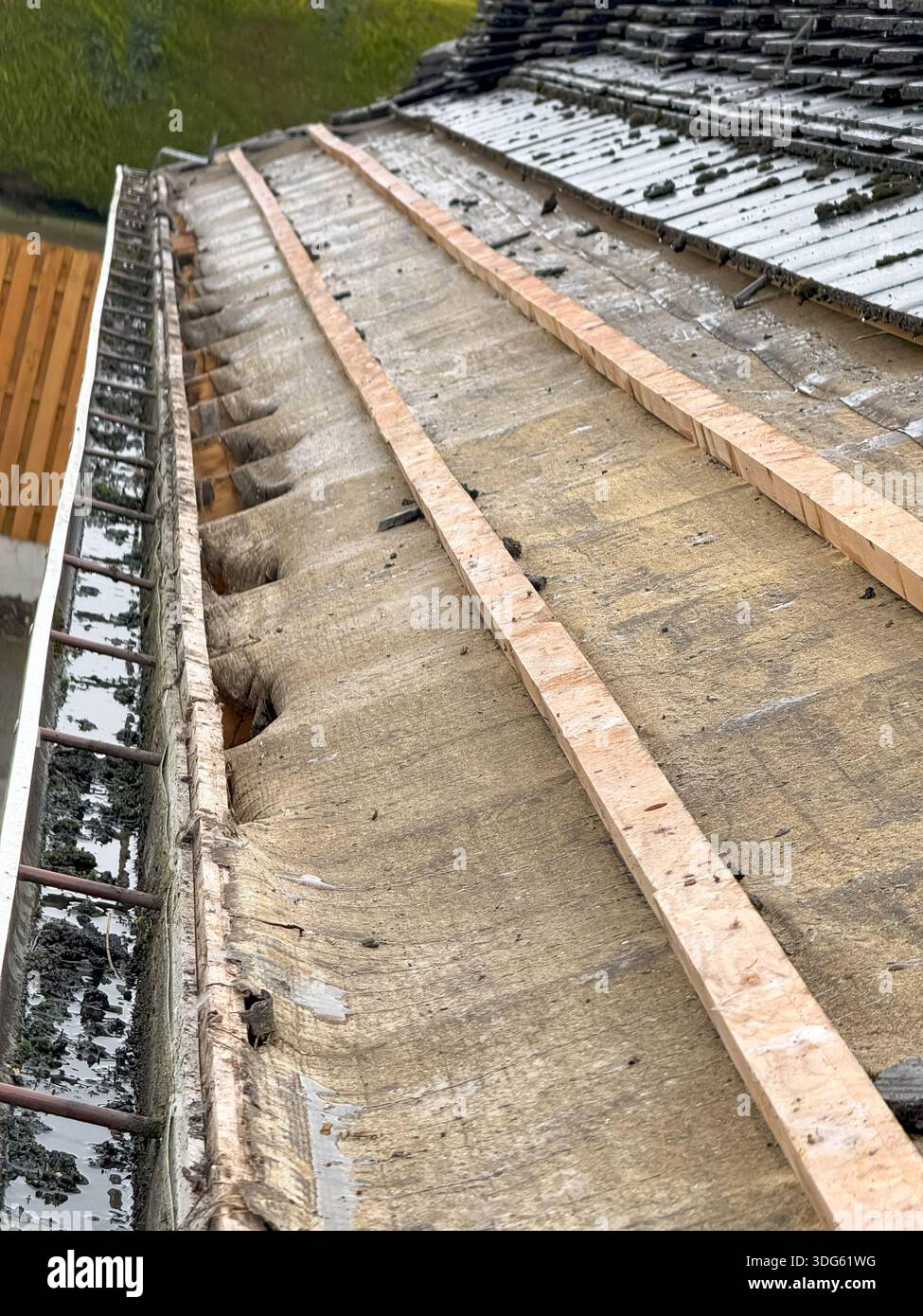 Damaged house roof with missing shingles after hurricane. Consequences of natural disaster. roof repair on a residential house Stock Photo