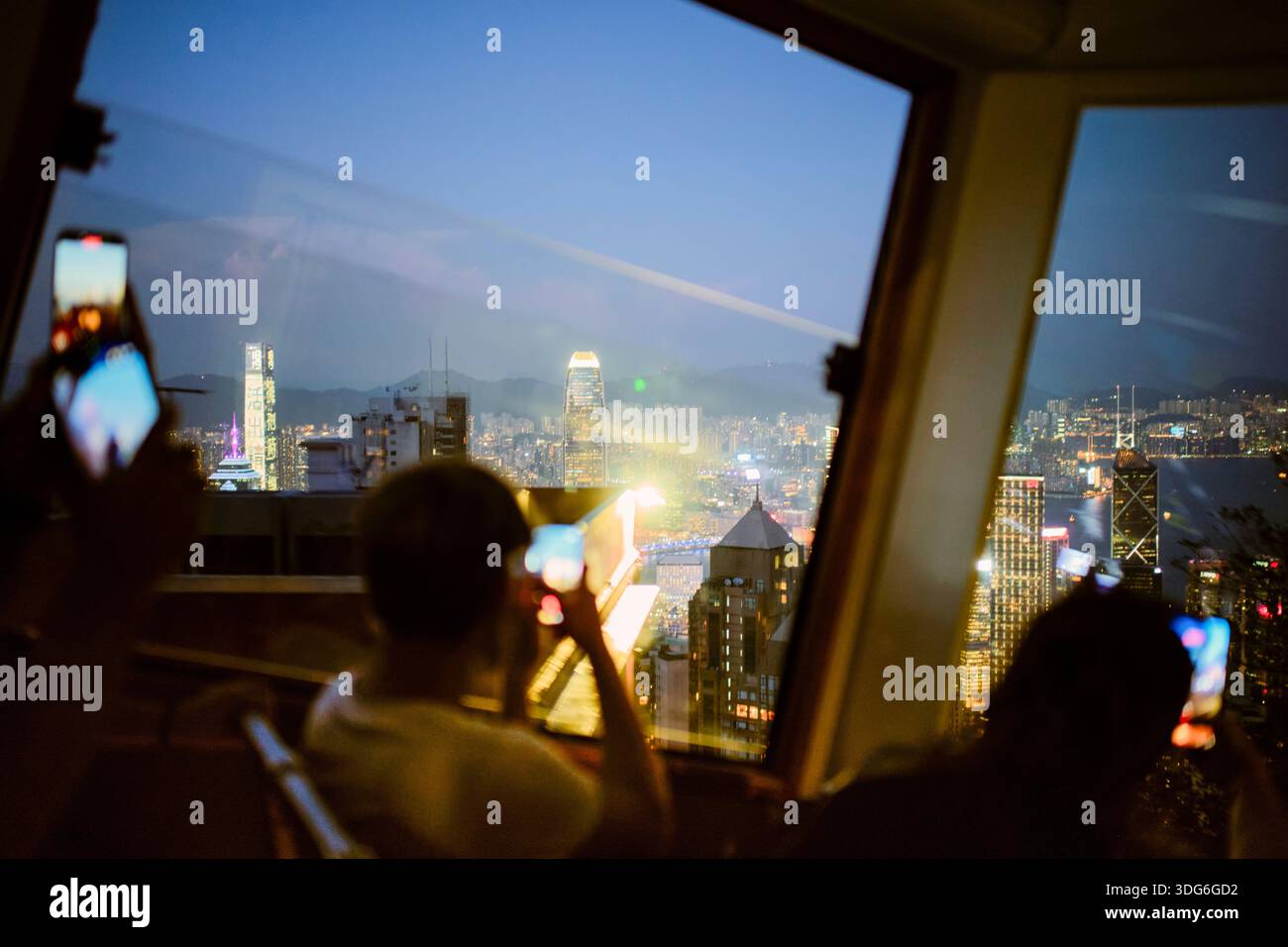 People inside a tram capture a vibrant cityscape through large windows ...