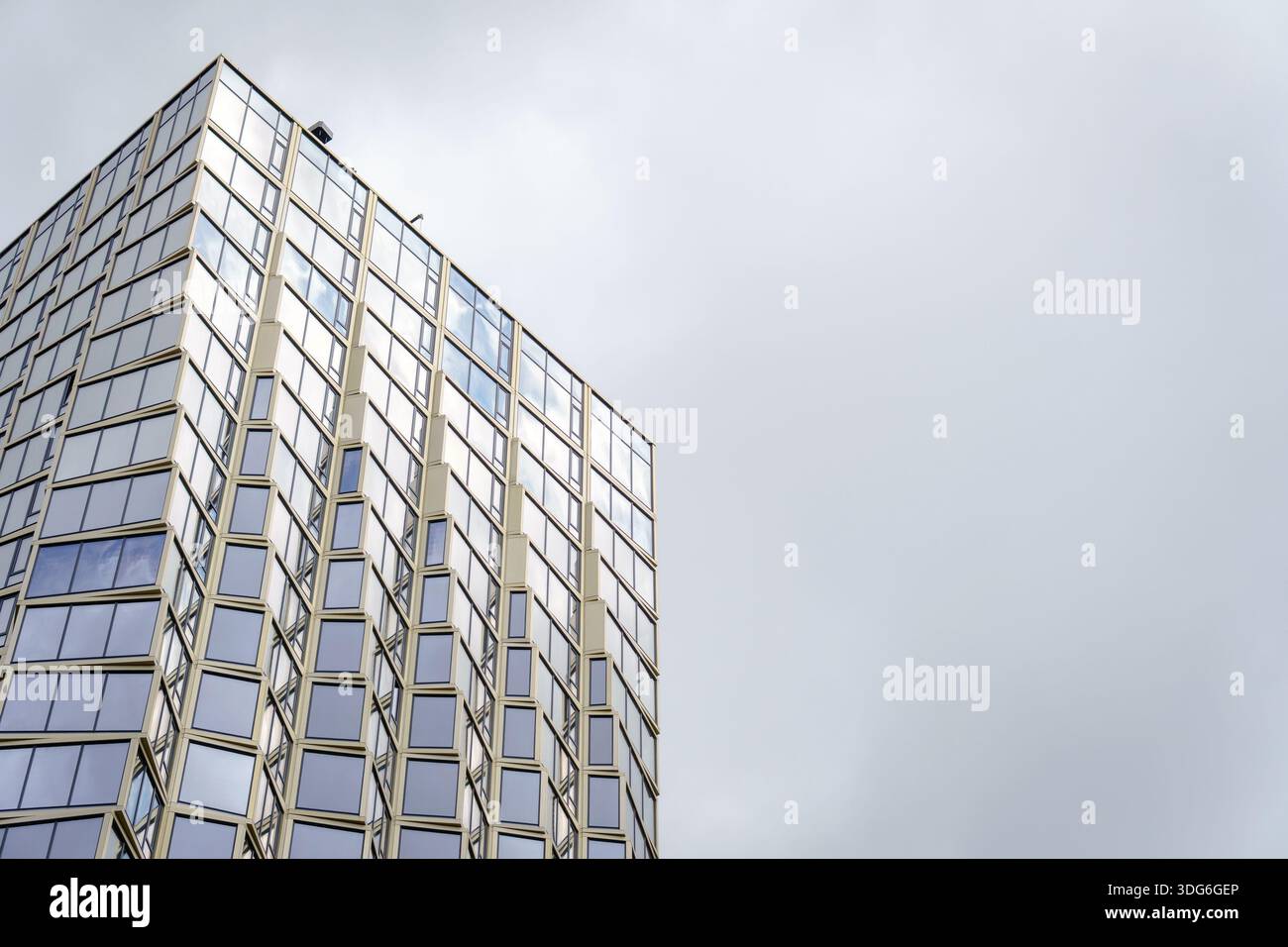 A modern high-rise building with a geometric facade and grid of windows ...