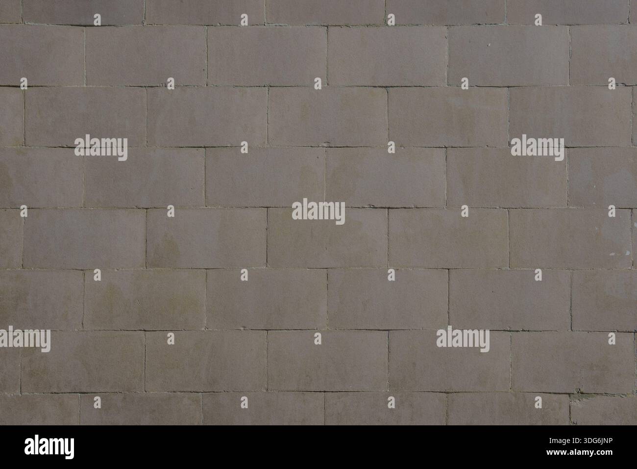 Wall surface covered with rectangular gray-brown tiles arranged in a staggered pattern. Tile shades vary slightly, with visible moisture marks and sig Stock Photo