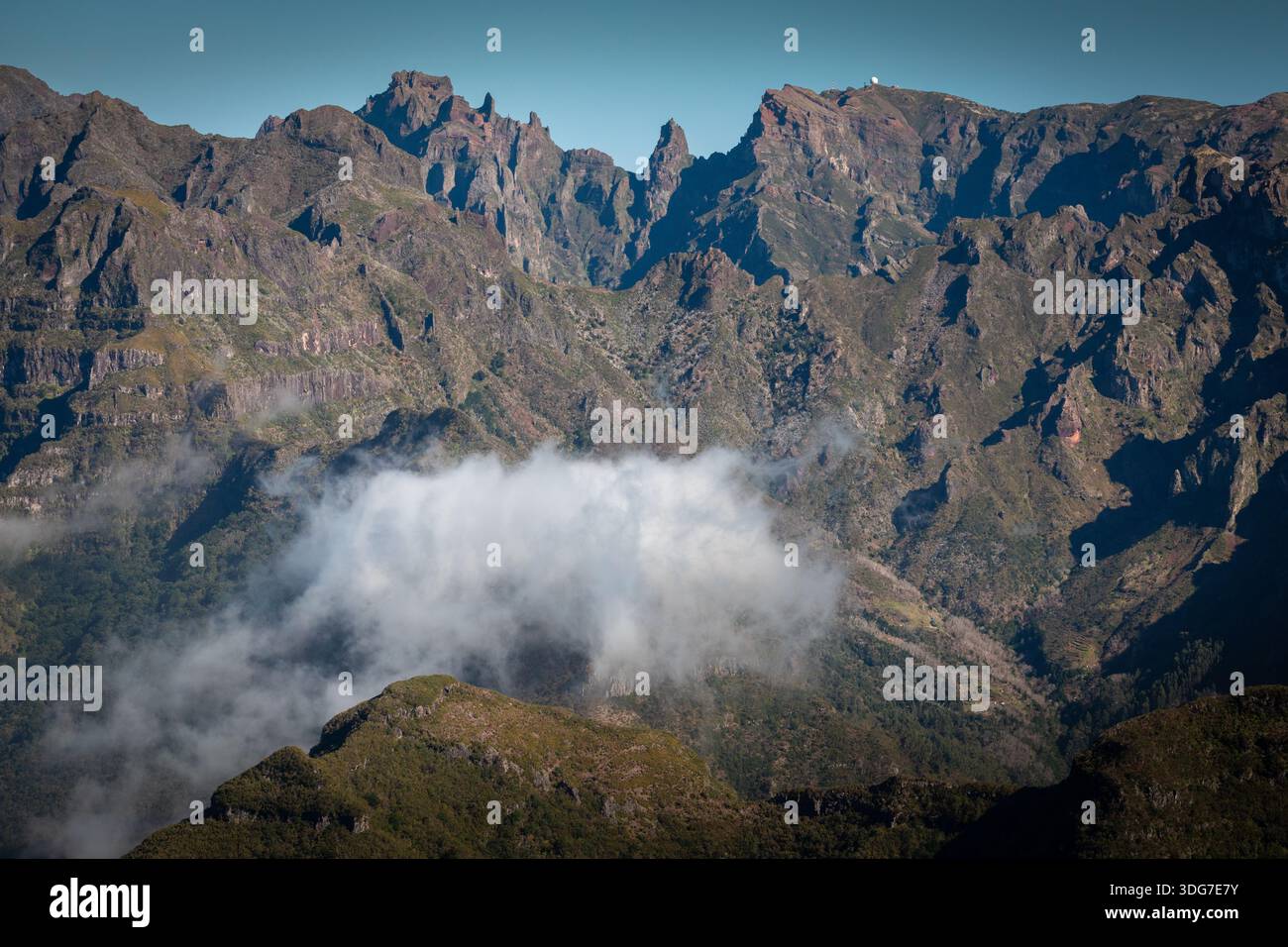 Rugged cliffs and sharp peaks of Madeira’s central mountain range rise above a floating layer of clouds, seen from Bica do Cana viewpoint on Madeira Stock Photo