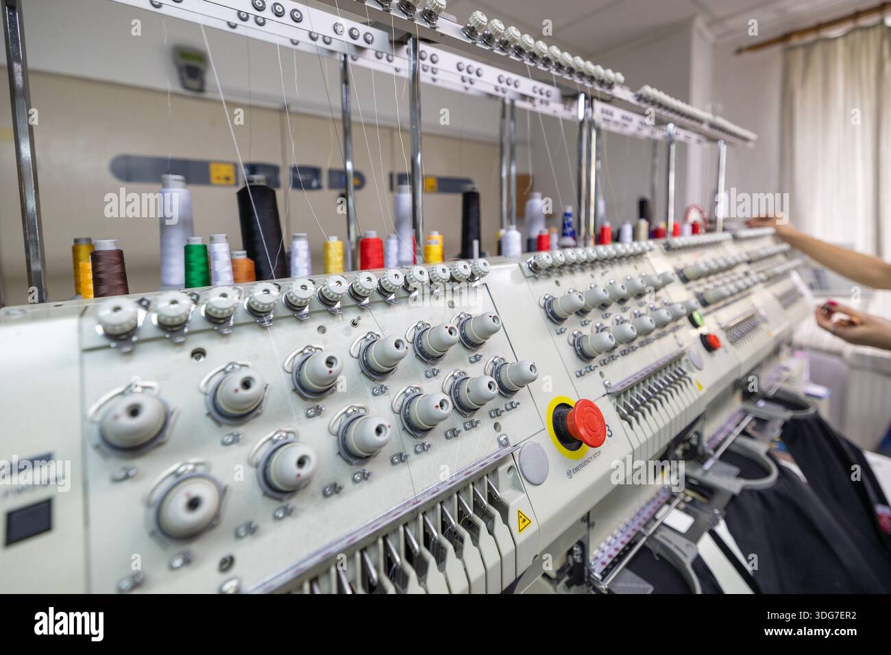 Colorful threads on industrial multi head embroidery machine. Automated equipment for branding restaurant uniforms and chef workwear in textile manufa Stock Photo