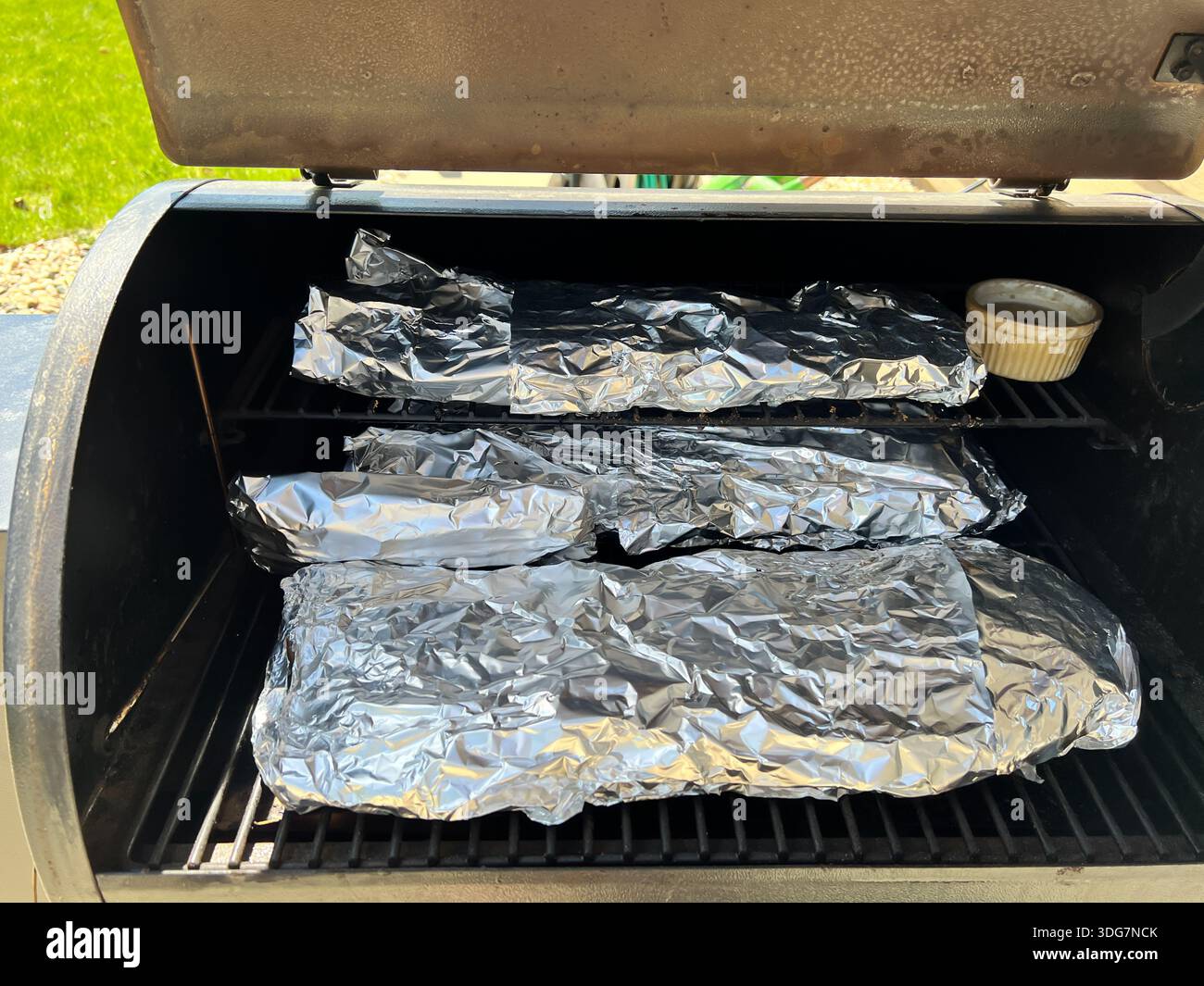 three racks of aluminum wrapped ribs in a bbq meat smoker Stock Photo ...