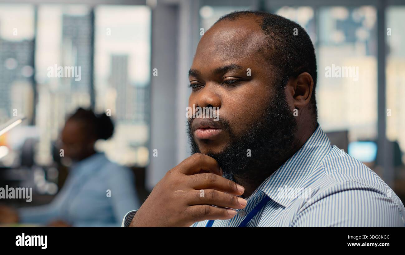 Close up of trader analyzing stock exchange analytics, doing thinking, evaluating trading strategy in prop firm office. African american man brainstorming, assesses risk in financial markets Stock Photo