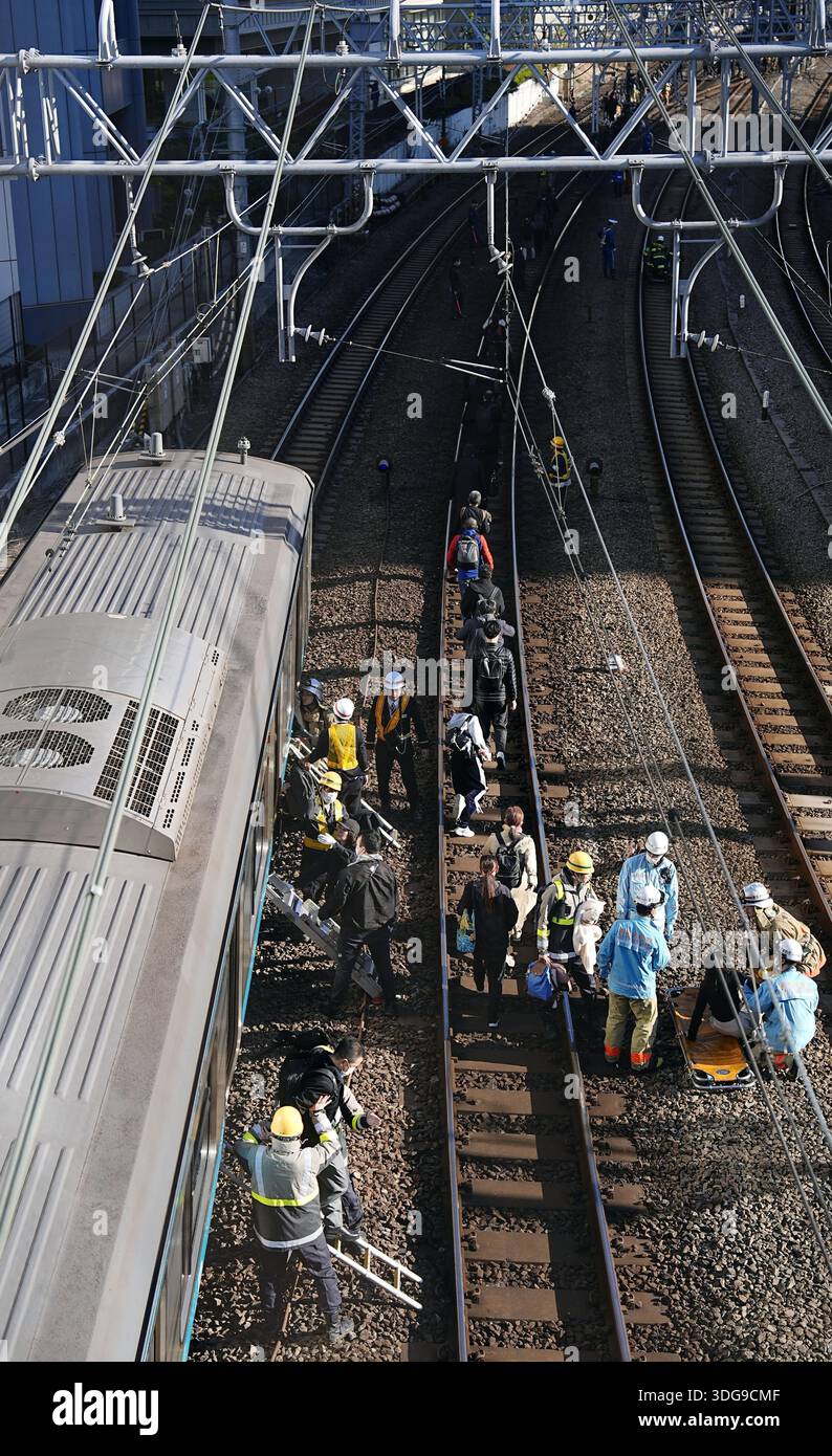Passengers get off a train with the help of railway company personnel ...