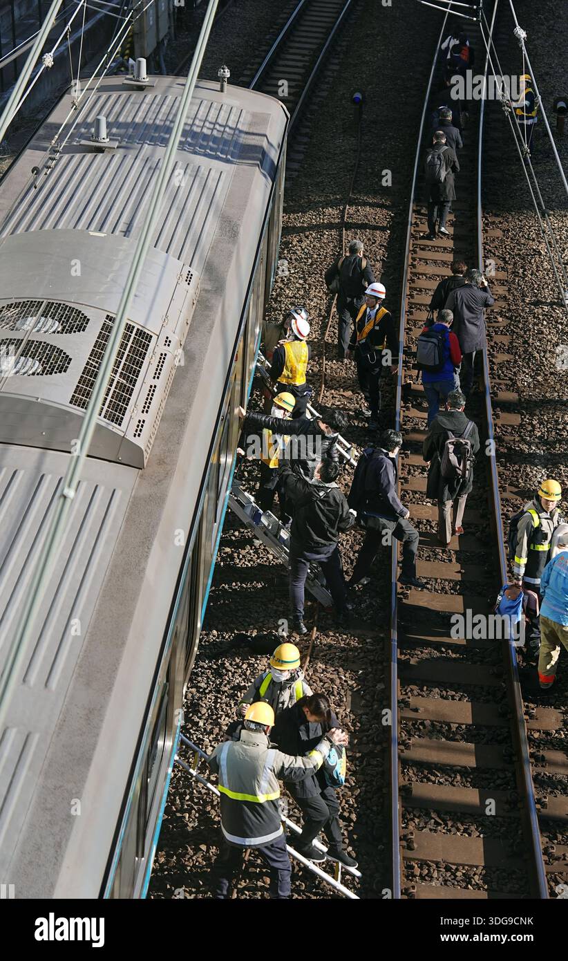Passengers get off a train with the help of railway company personnel ...