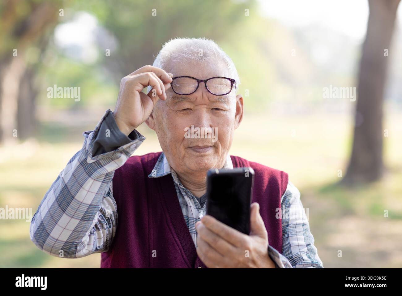 Poor Eyesight. Senior  Man Using Smartphone Wearing Eyeglasses Stock Photo